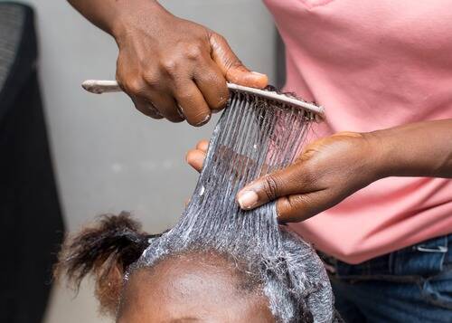 Stylist Applying Hair Relaxer on Client