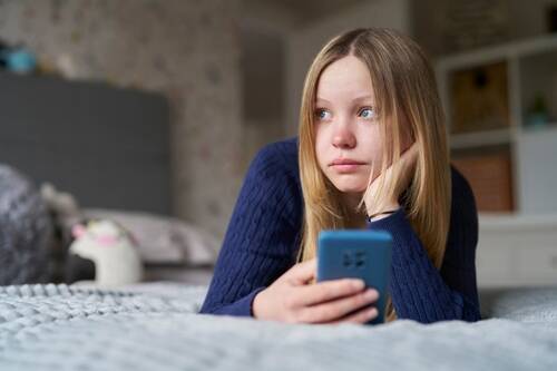 Boston Social Media Addiction Lawsuit An image of a young girl holding her phone in her bedroom due to social media represents a social media addiction lawsuit case.
